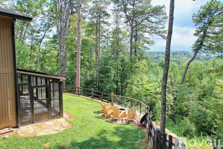 A wooden deck with a glass door overlooks a lush green forest.