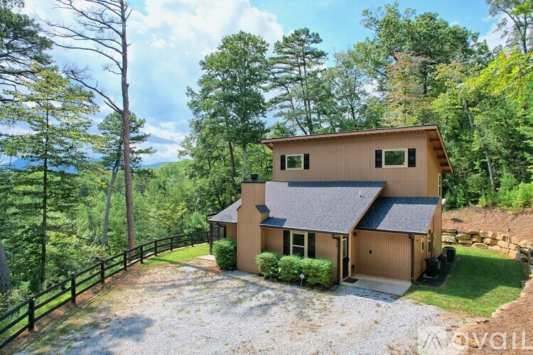A house with a gravel driveway is surrounded by trees.
