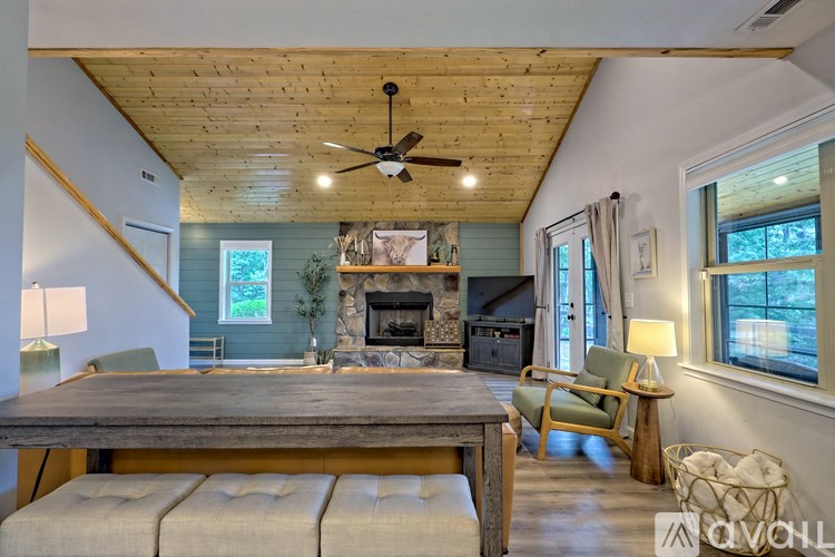 A cozy living room with a fireplace and a wooden ceiling.