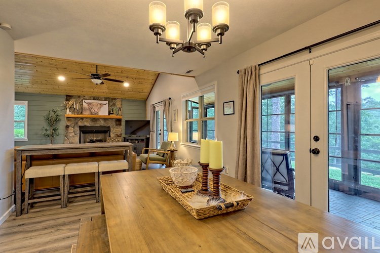 A wooden table with candles on a tray in a room with a chandelier.