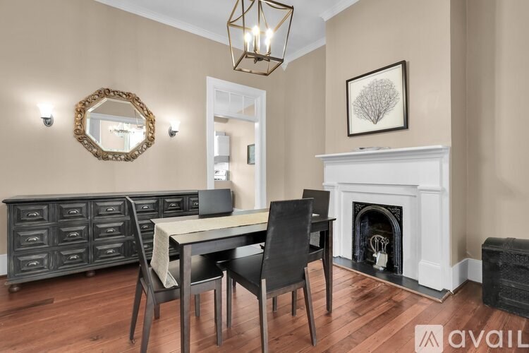 A dining room with a white table and chairs, a fireplace, and a mirror on the wall.