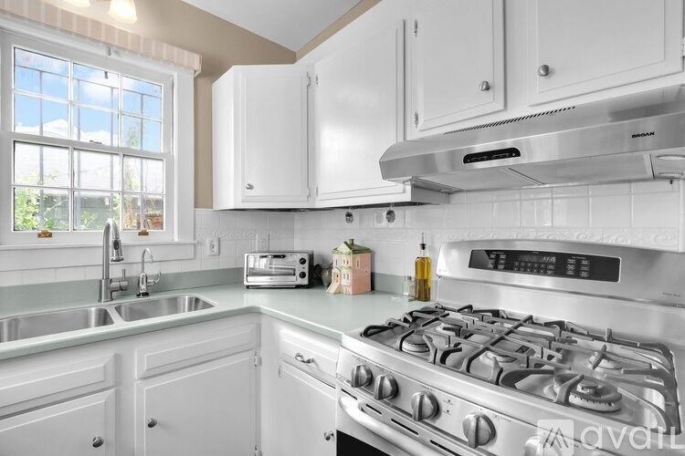 A kitchen with white cabinets and a stainless steel gas stove.