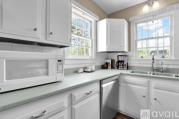 A white kitchen with a microwave, sink, and cabinets.