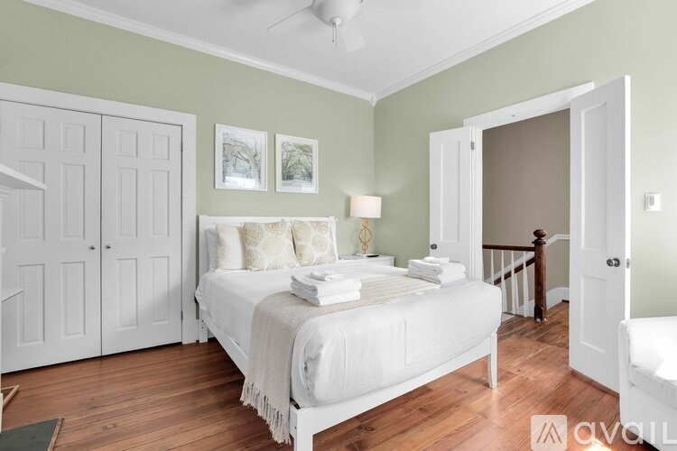 A bedroom with a bed, a chair, and a ceiling fan.