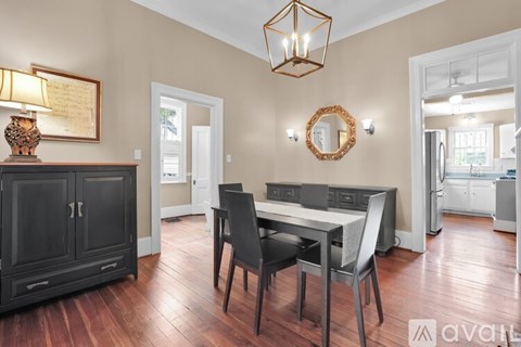 A kitchen with a table and chairs in the foreground and a framed paper on the wall.