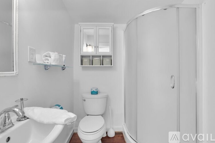 A white bathroom with a sink, toilet, and shower.