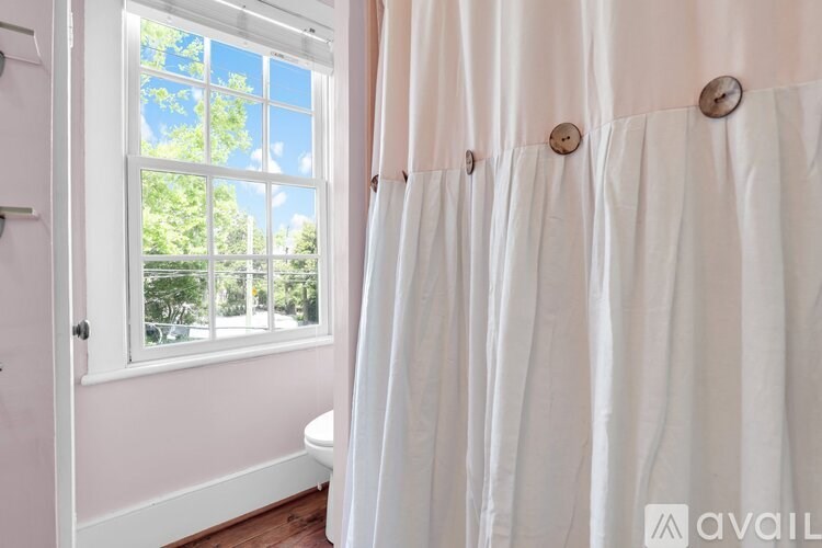 A bathroom with a window and a white shower curtain.
