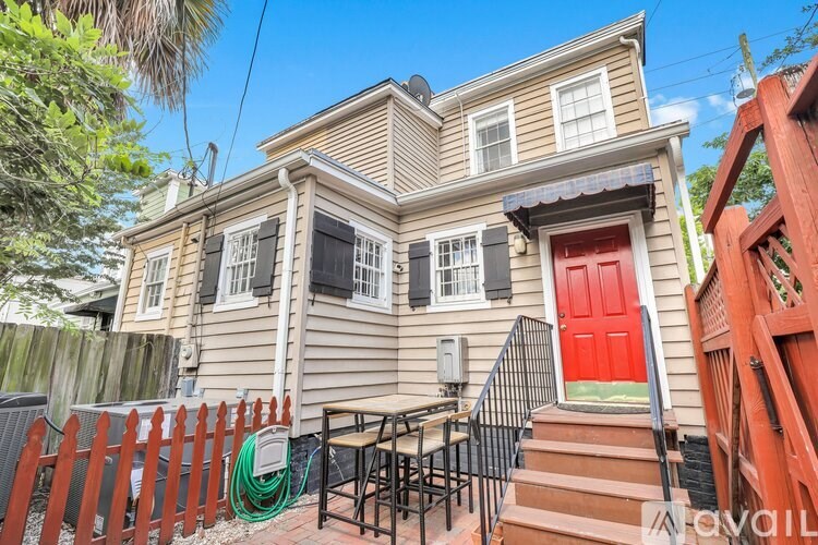 A two-story house with a red door and a red fence.