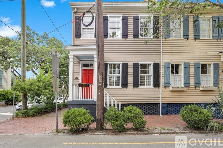 A two-story house with a red door and green shutters.