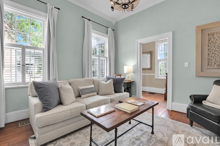 A living room with a couch, a coffee table, and a chandelier.