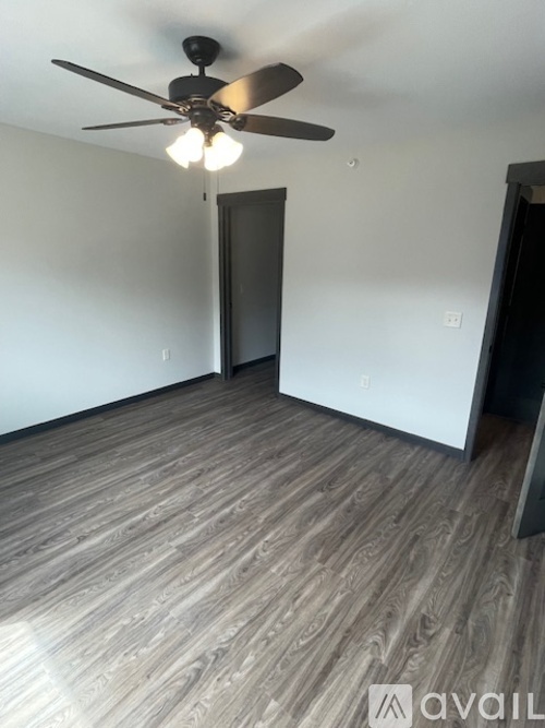 A room with a ceiling fan and wooden flooring.