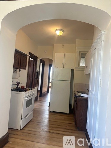 A kitchen with white appliances and wooden floors.