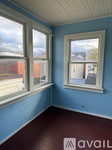 A room with blue walls and a window overlooking a street.