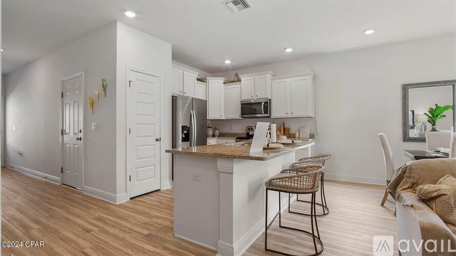 A kitchen with white cabinets and a wooden floor.