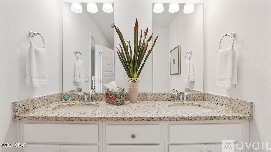 A bathroom with a marble countertop and a vase with red leaves.