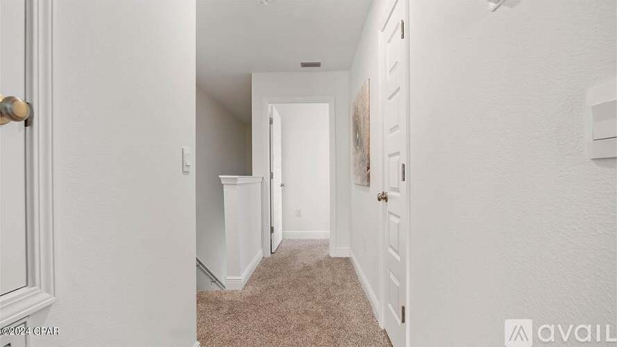 A hallway with a carpeted floor and white walls.