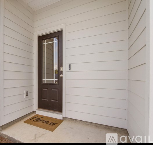 A brown door with a glass window is set in a white wall.