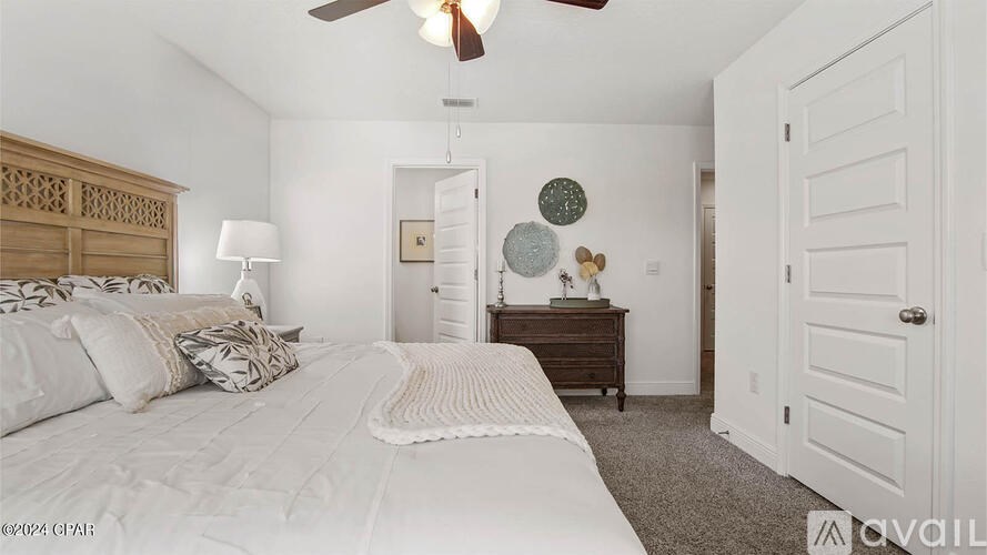 A bedroom with a large bed and a ceiling fan.