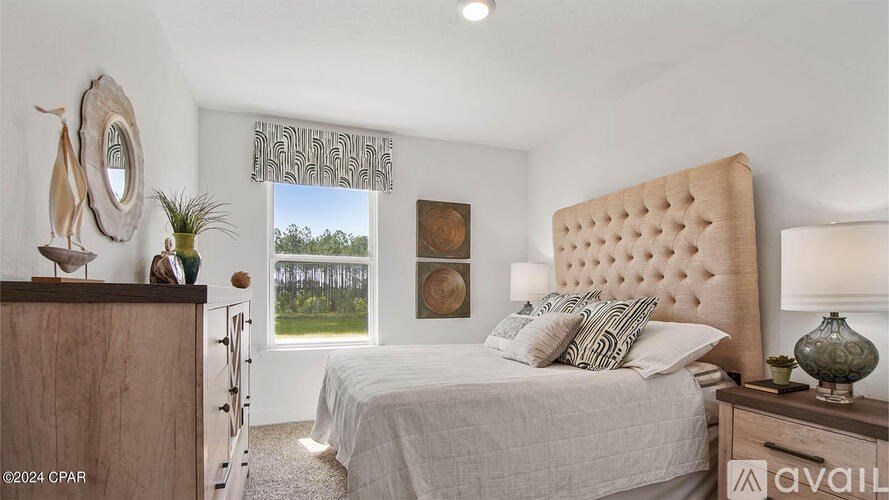 A bedroom with a large bed and a window overlooking a field.