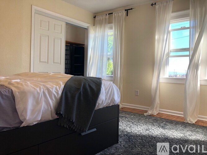 A bedroom with a large bed and a window with curtains.