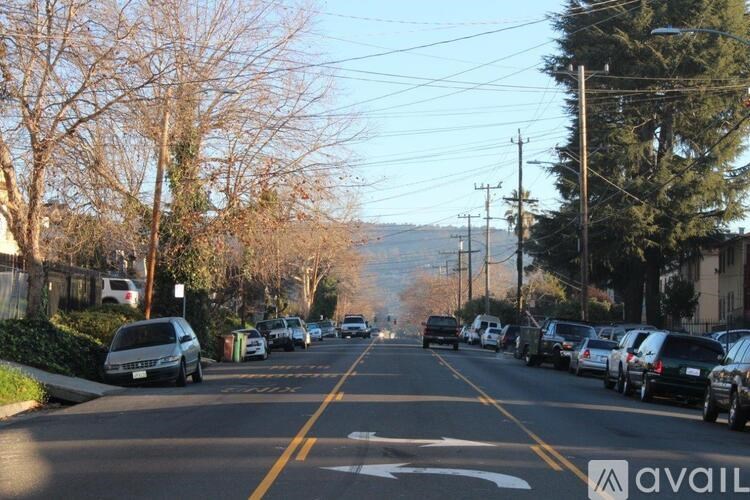 A street with cars parked on both sides and a mountain in the distance.