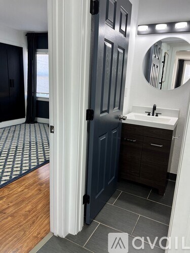 A bathroom with a sink, mirror, and wooden floors.