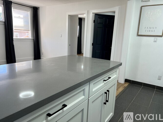 A kitchen with a grey countertop and white cabinets.