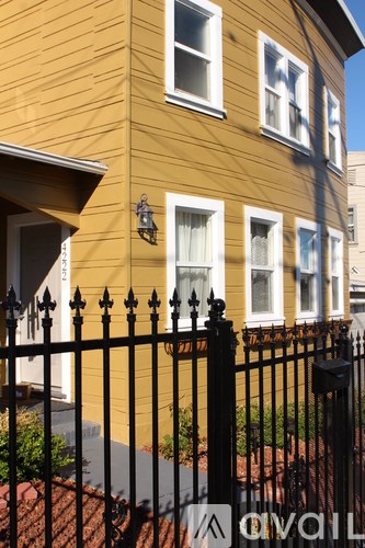 A yellow house with a black fence in front.