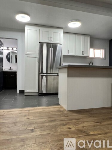 A kitchen with white cabinets and a wooden floor.