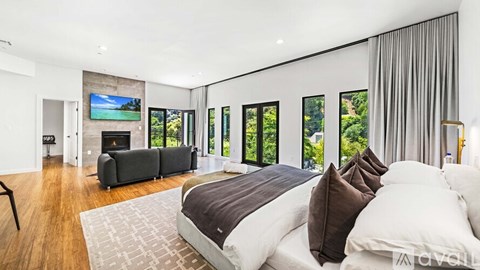 A modern bedroom with a large bed and a fireplace.
