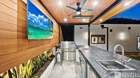 A modern kitchen with a wooden wall and a ceiling fan.