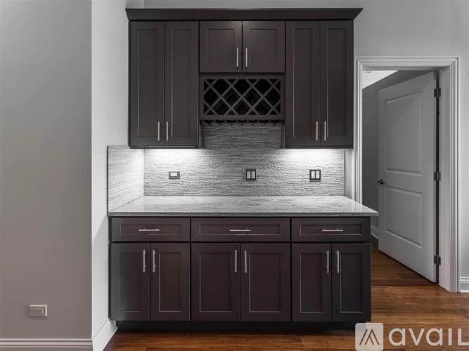 A kitchen with dark brown cabinets and a marble countertop.