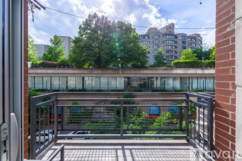 A balcony with a metal railing and a brick wall on the left side.