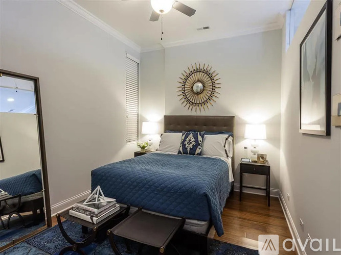 A bedroom with a bed, nightstand, and a mirror on the wall.