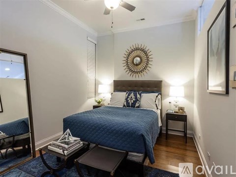 A bedroom with a bed, nightstand, and a mirror on the wall.
