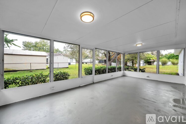 A spacious room with large windows and a view of a green outdoor area.