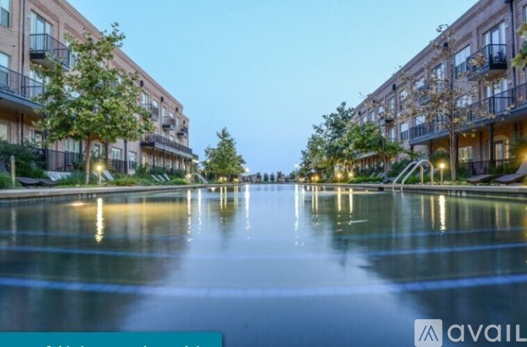 A calm body of water reflects the lights of apartment buildings.
