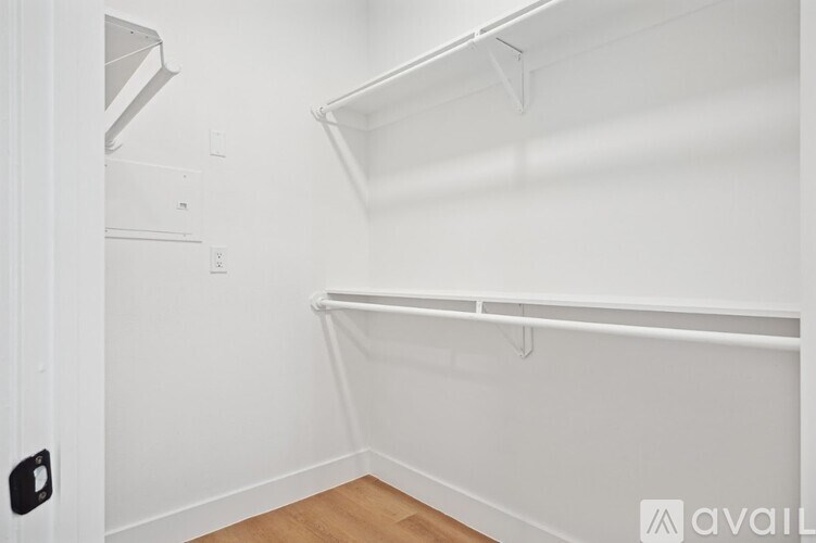 A white closet with a white shelf and a white door.