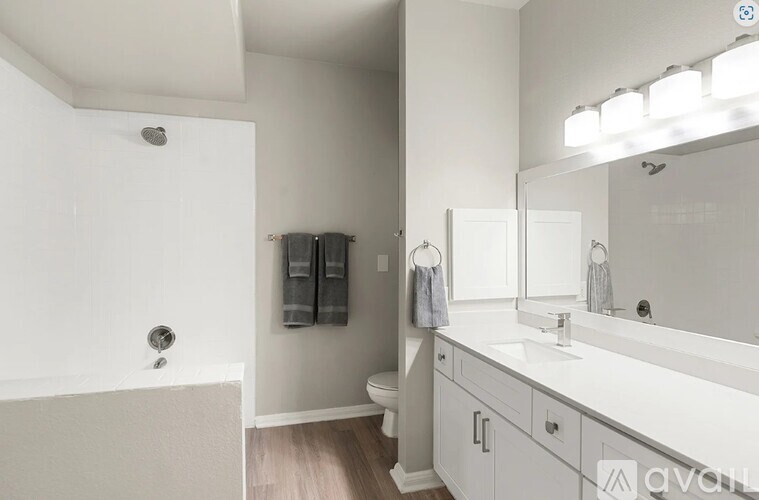 A white bathroom with a sink, mirror, and toilet.