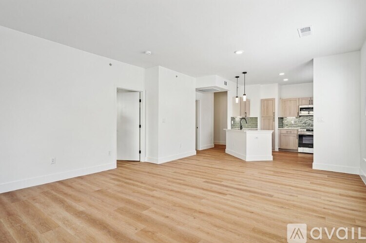 A spacious room with wooden flooring and white walls.