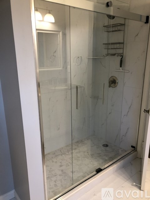A bathroom with a marble floor and a walk-in shower.