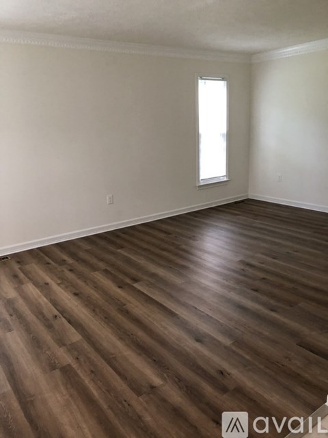 A room with wooden flooring and a window.