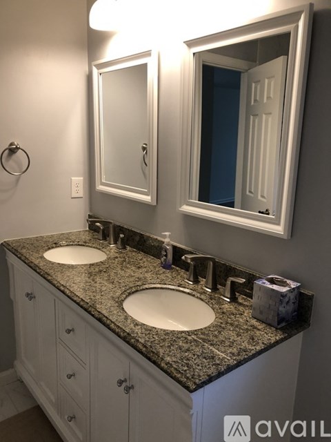 A bathroom with a granite countertop and a large mirror above the double sinks.