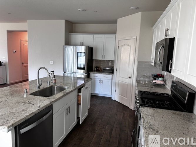 A kitchen with white cabinets and a granite countertop.