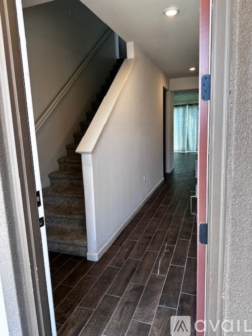 A hallway with a staircase and a door on the right.