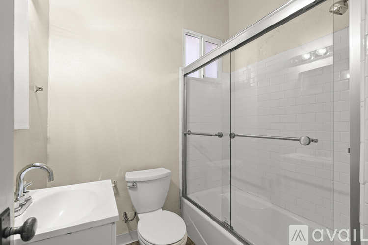 A bathroom with a toilet, sink, and glass shower stall.