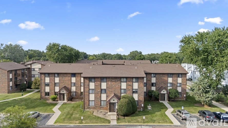 A large brick apartment building with a parking lot in front.