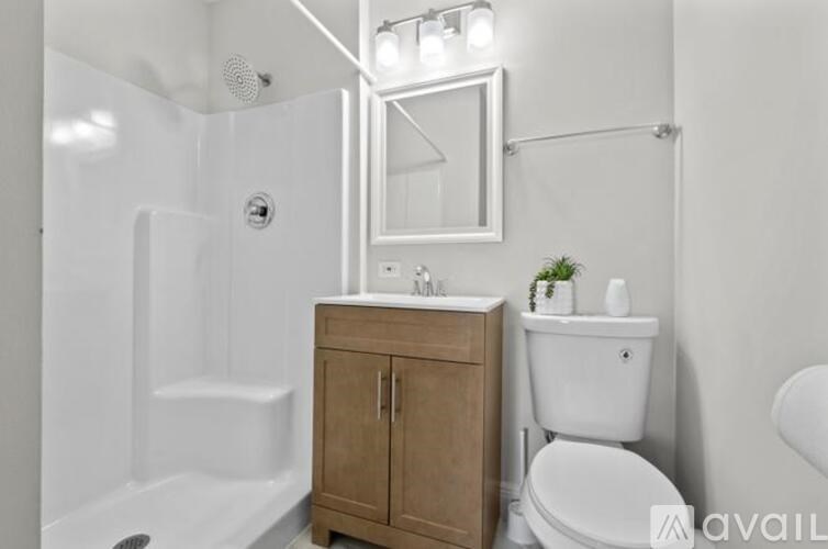 A bathroom with a white toilet, a white sink, a wooden cabinet, and a white bathtub.
