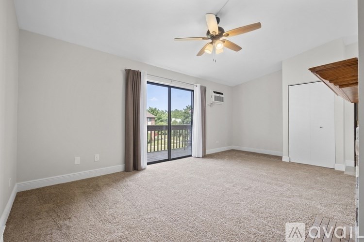A living room with a ceiling fan and sliding glass doors leading to a balcony.