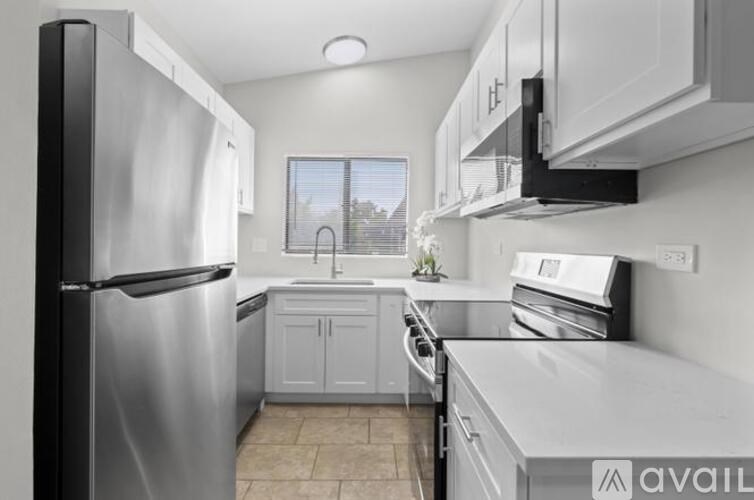 A kitchen with a stainless steel refrigerator and white cabinets.